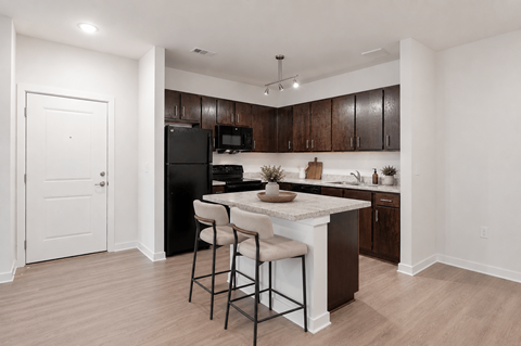 A kitchen with a black refrigerator and brown cabinets.