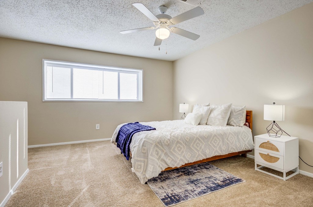The Pearl at Highland Village Apartments and Townhomes for rent in Jackson, MS photo of a bedroom with a bed and a ceiling fan