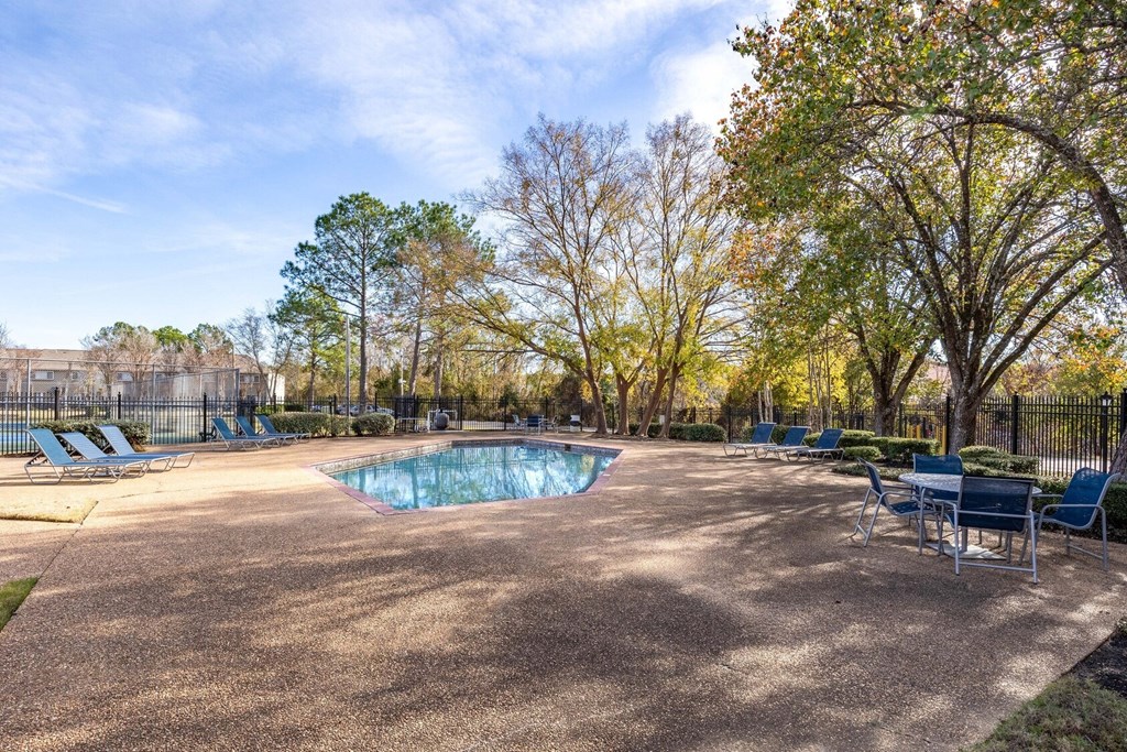 The Pearl at Highland Village Apartments and Townhomes for rent in Jackson, MS photo of a resort style pool with chairs around it and trees
