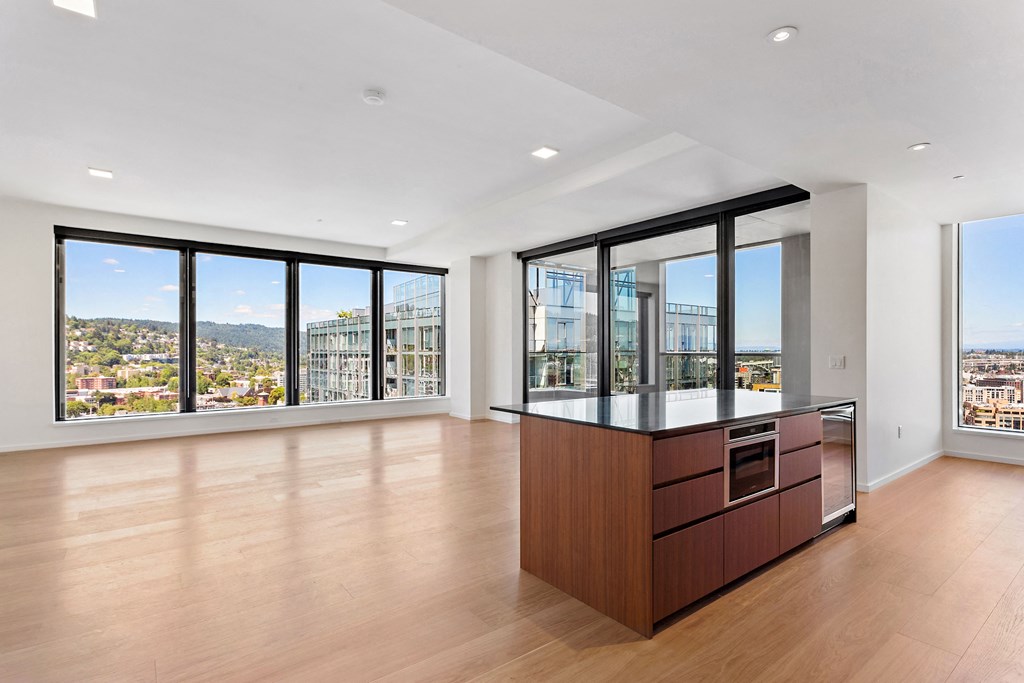a living area with hardwood flooring and a large window with a view of the city