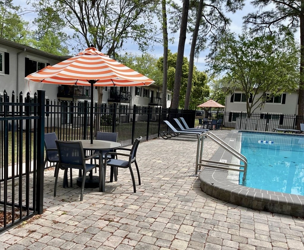 a swimming pool with a table with an umbrella and chairs