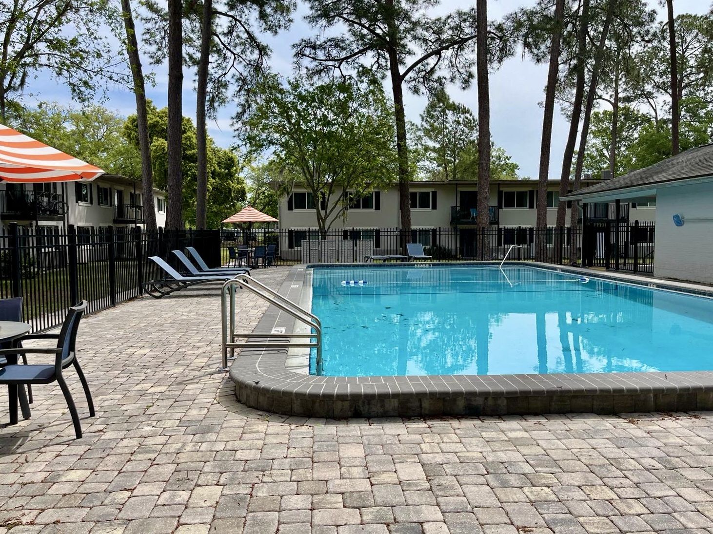 a resort style swimming pool with chairs and trees