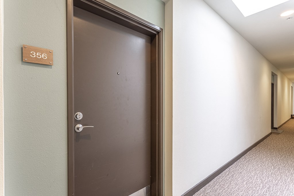 a metal door in a hallway with a clock on the wall next to it