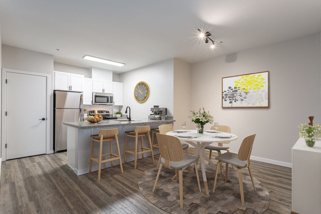 Pet Friendly Apartments in Sherwood OR - Cannery Row - Kitchen with Wood-Style Floor, Stainless Steel Appliances, White Cabinets, Granite-Style Countertops, Breakfast Bar with Stools, and 4-Seater Round Dining Set