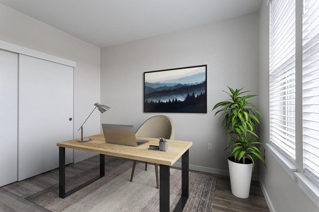 close up of a desk with a laptop and a painting of a mountain
