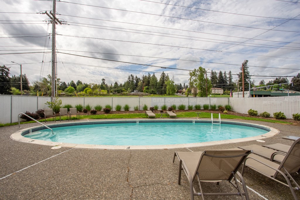 a swimming pool with chairs and a fence around it