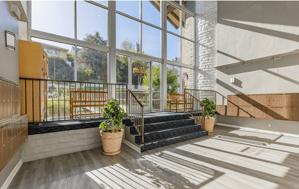 a large glass walled building with a staircase and potted plants in front of it