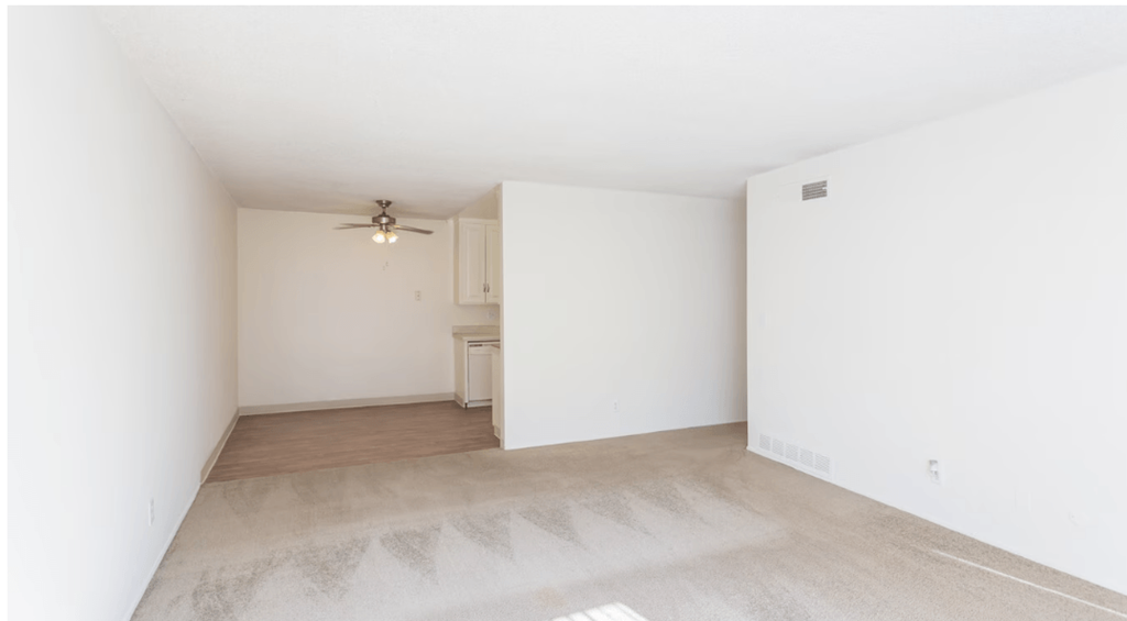 a bedroom with white walls and a ceiling fan