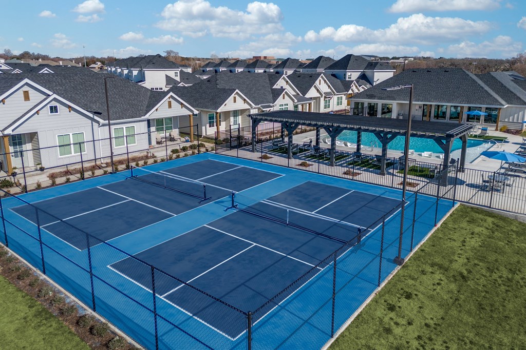 A tennis court with a blue surface and a black fence.