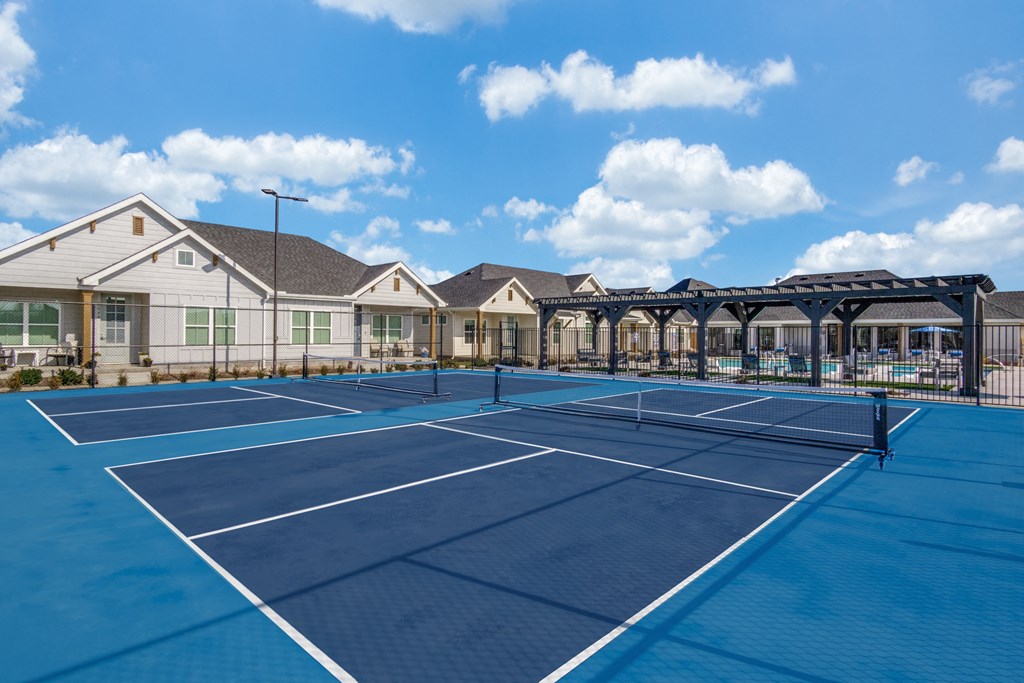 A tennis court is surrounded by houses.