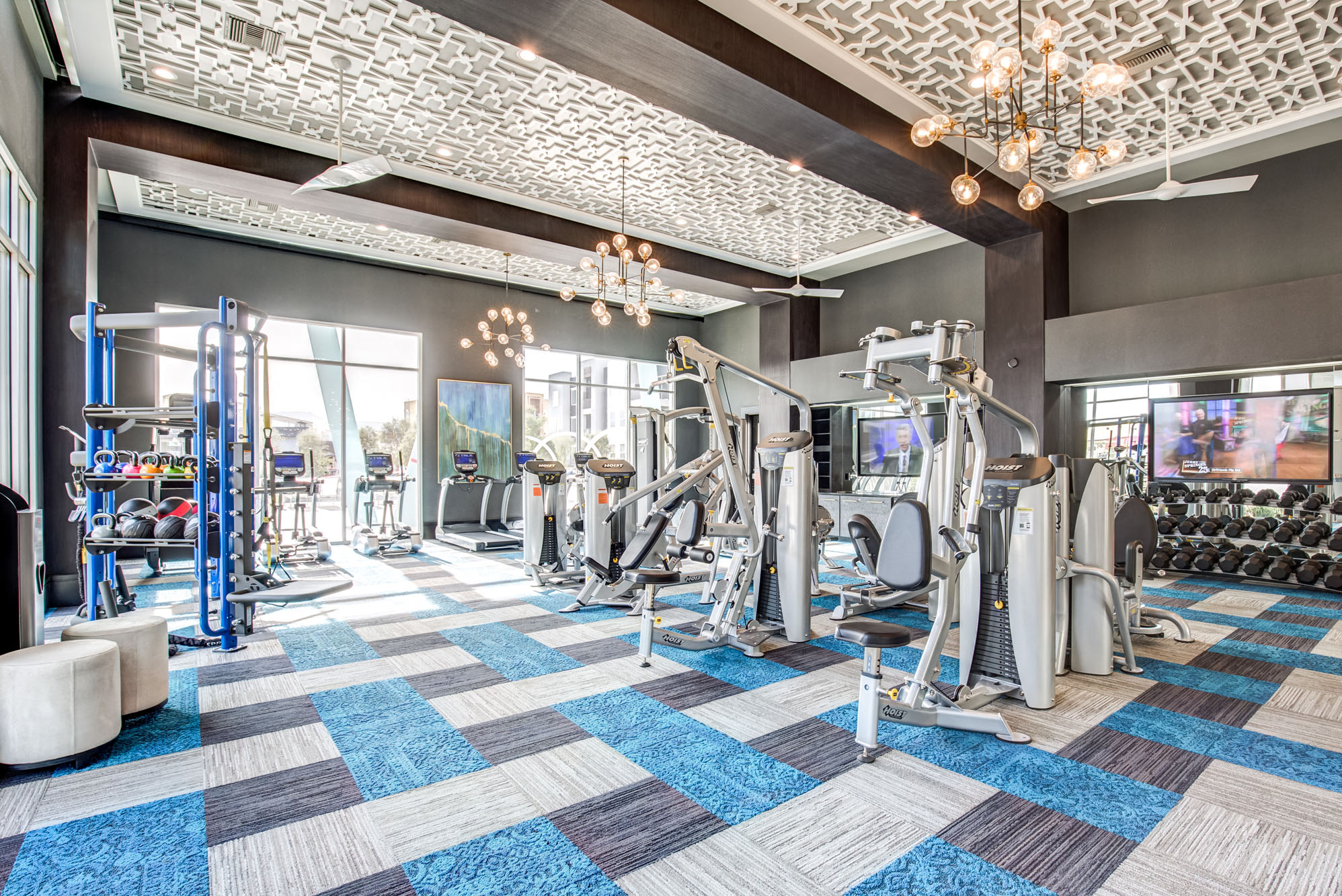 a gym with weights and cardio equipment in a room with glass doors