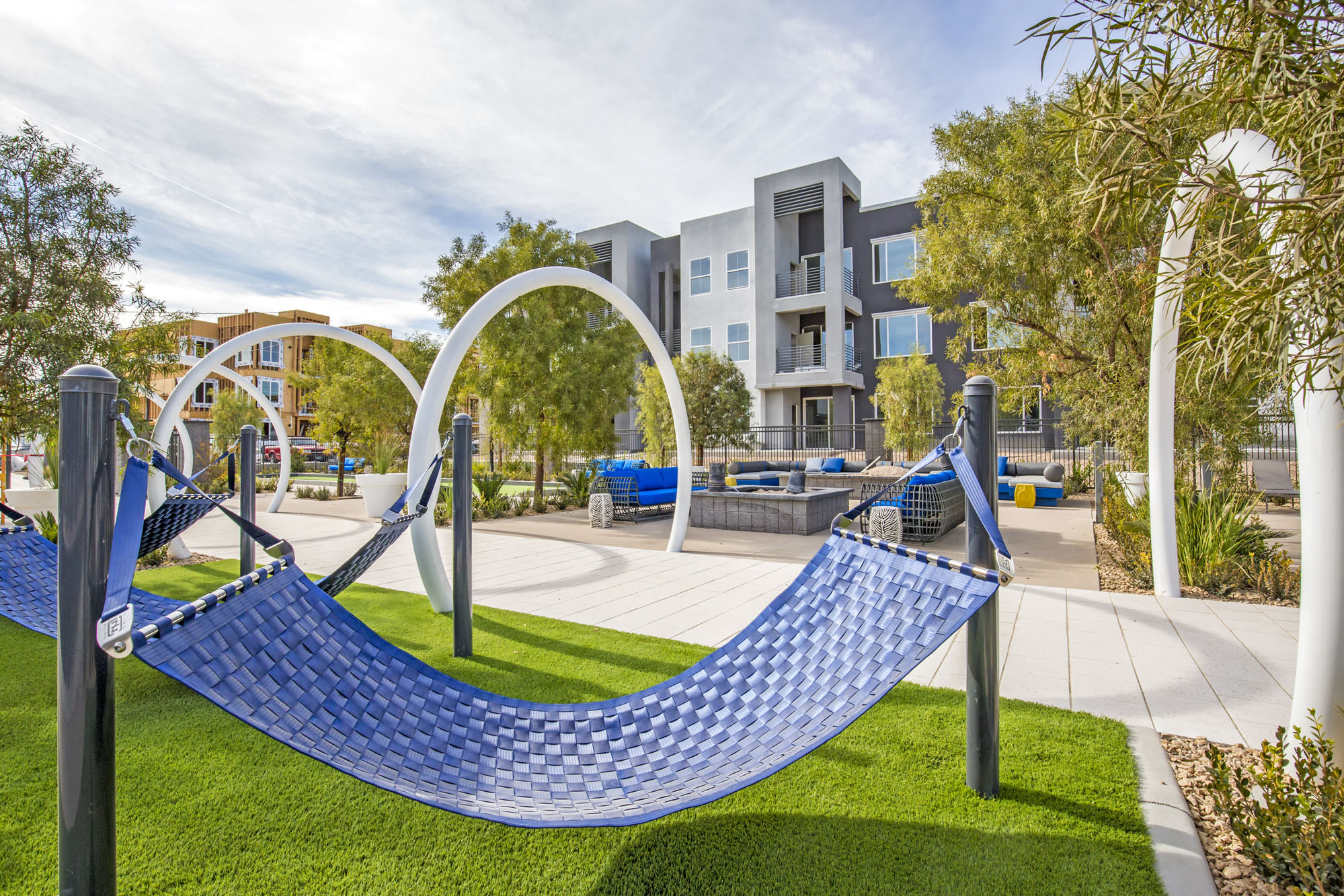 a hammock area in a park with an apartment building in the background