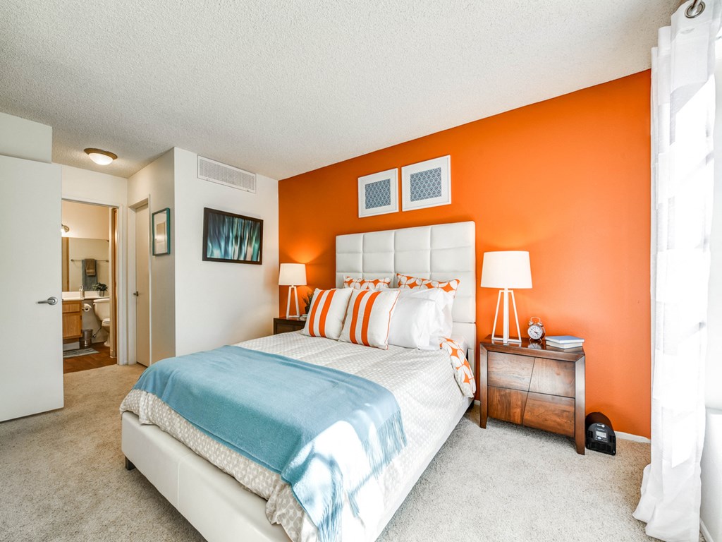 the master bedroom has a large bed and an orange accent wall