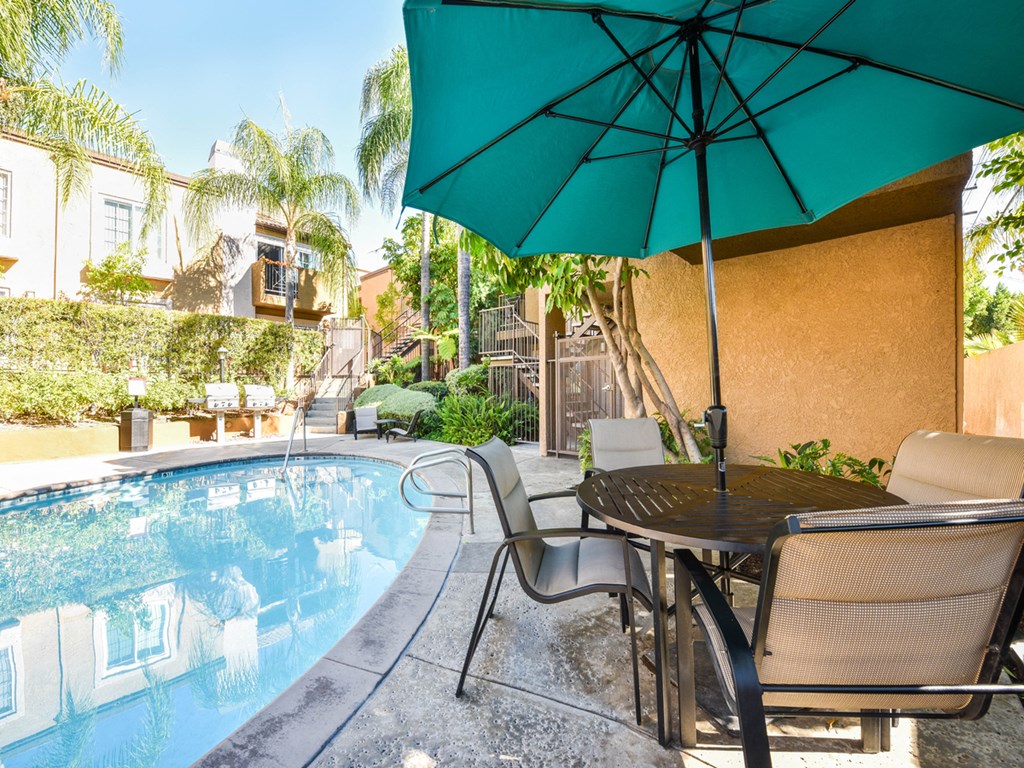 a swimming pool with a table and chairs under an umbrella