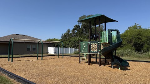 A playground with a green slide and a sign with letters and numbers.
