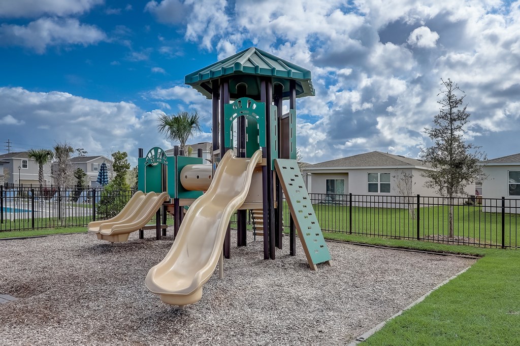A playground with a green slide and a wooden slide.