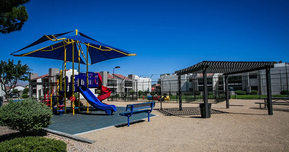 a playground with a blue umbrella and a blue bench