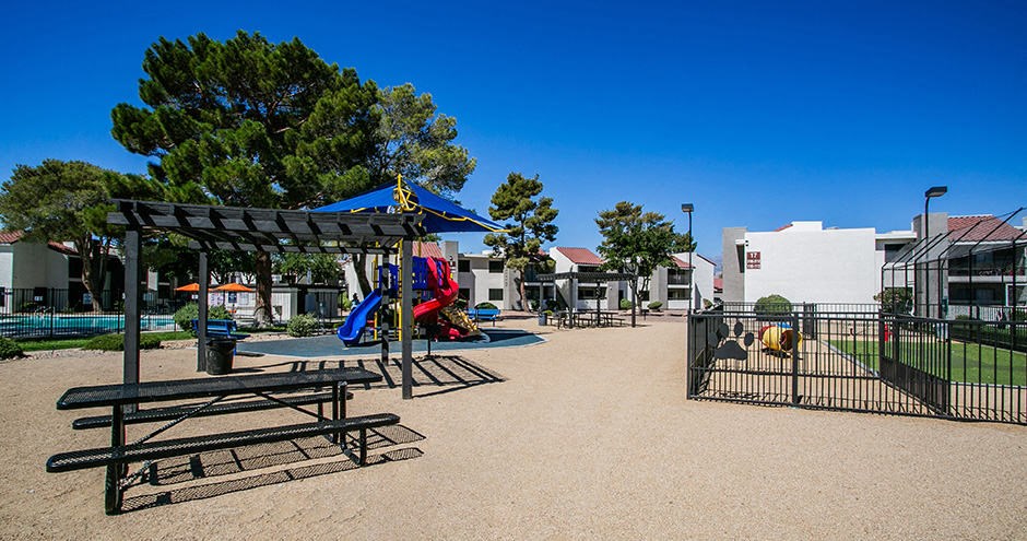 a playground with picnic tables and swings in a park