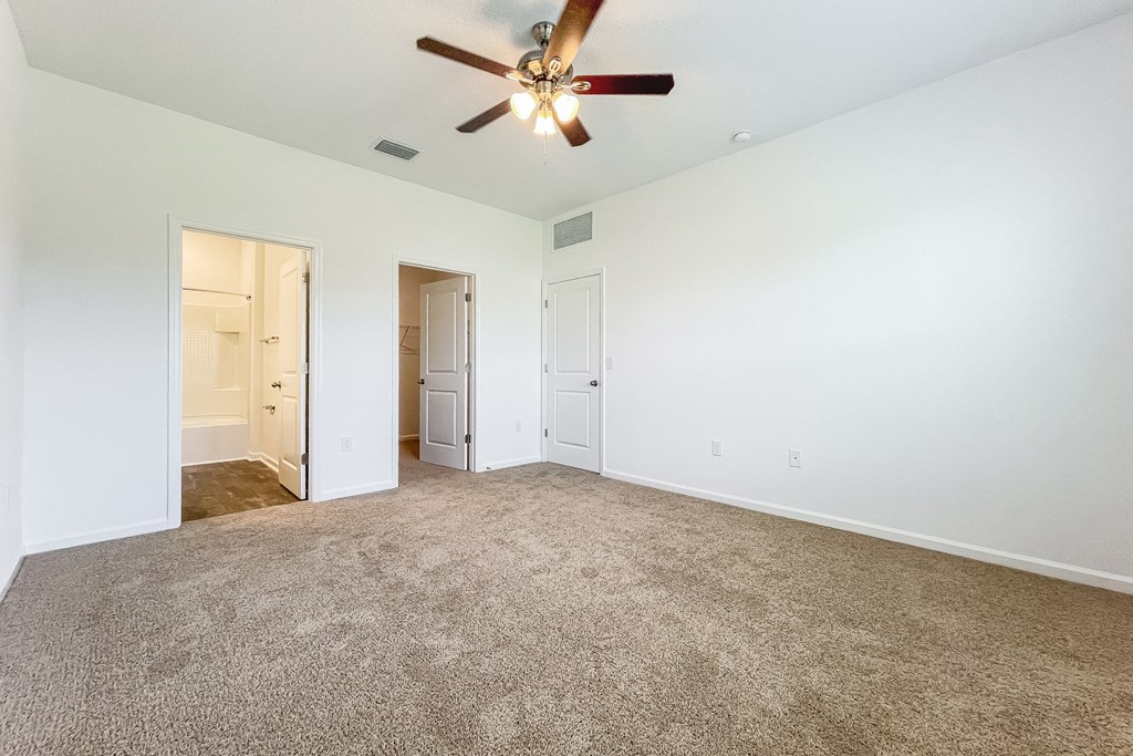 A room with a ceiling fan and carpeted floor.