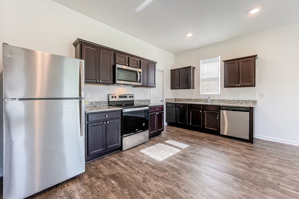 A kitchen with dark brown cabinets and a stainless steel refrigerator.