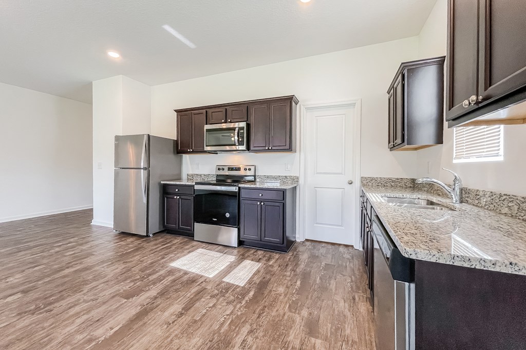 A kitchen with dark brown cabinets and a white door.