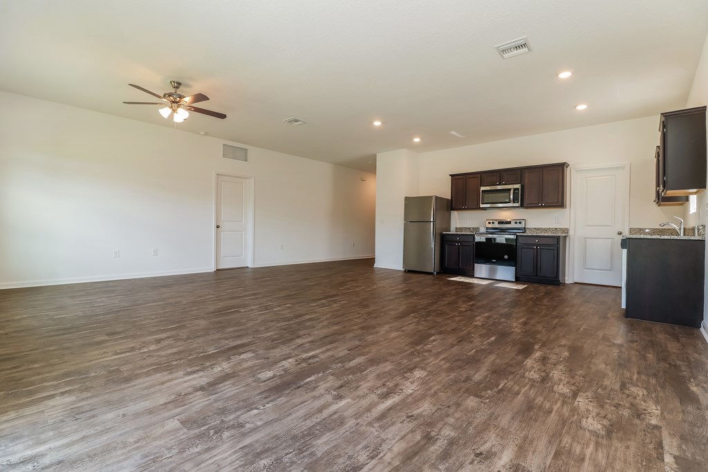 A spacious living room with a kitchen area in the background.