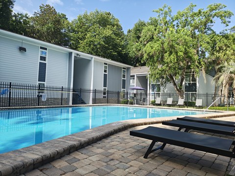 A pool surrounded by a black fence and a bench.