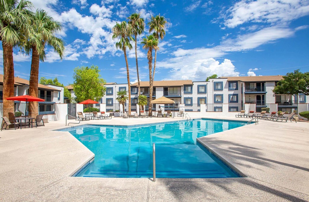Tuscon, AZ Apartments - Peaks at Redington - Swimming Pool Surrounded By Lounge Chairs, Umbrellas, and Palm Trees