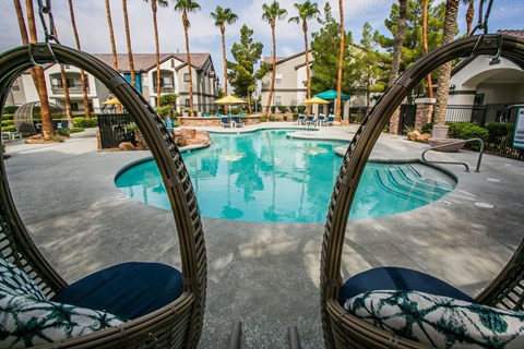 A swimming pool surrounded by palm trees and apartment buildings.
