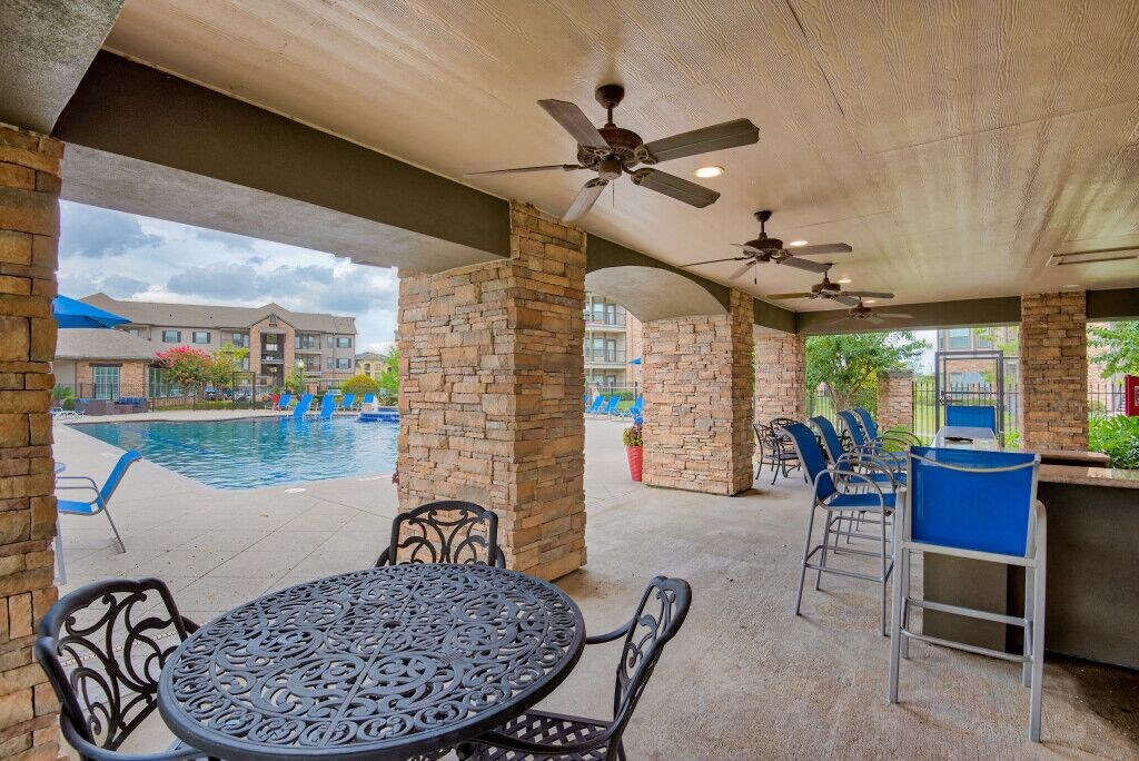 Relaxing area near pool with tables and chairs and fan