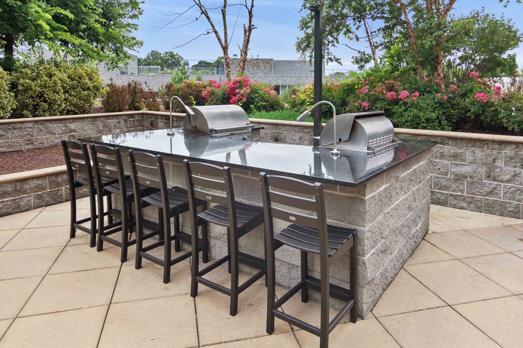 outdoor kitchen with stainless steel grills and bar seating