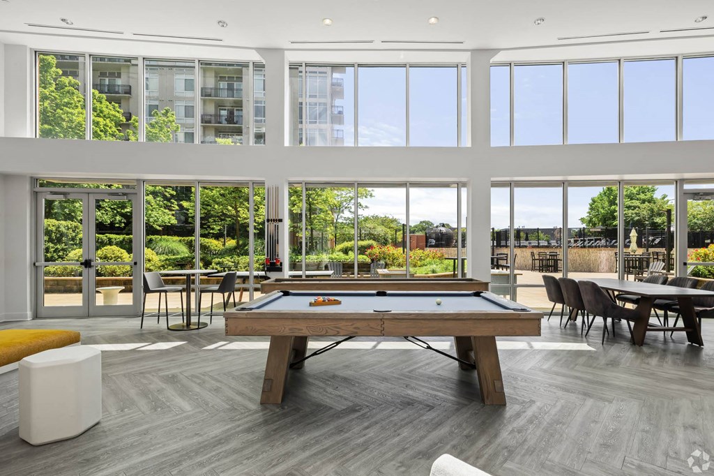 a pool table in a living room with large windows