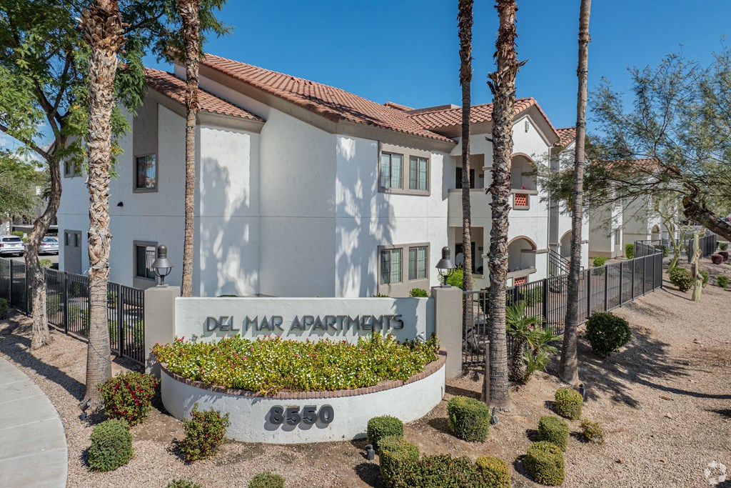 A white building with a red roof and a sign that says Del Mar Apartments.