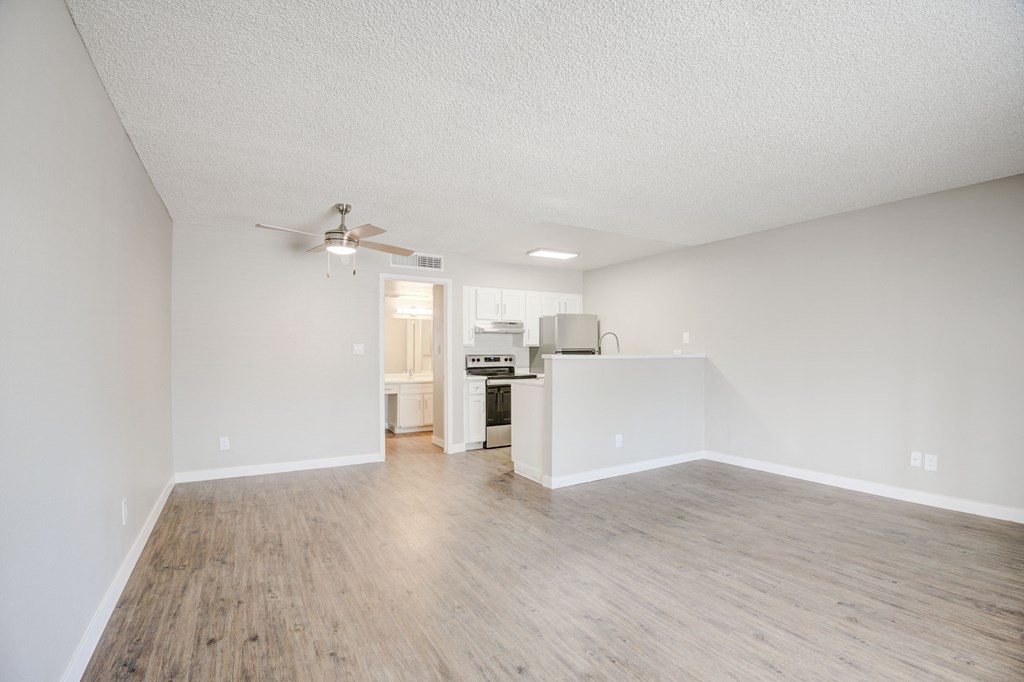 a spacious living room with a kitchen in the background