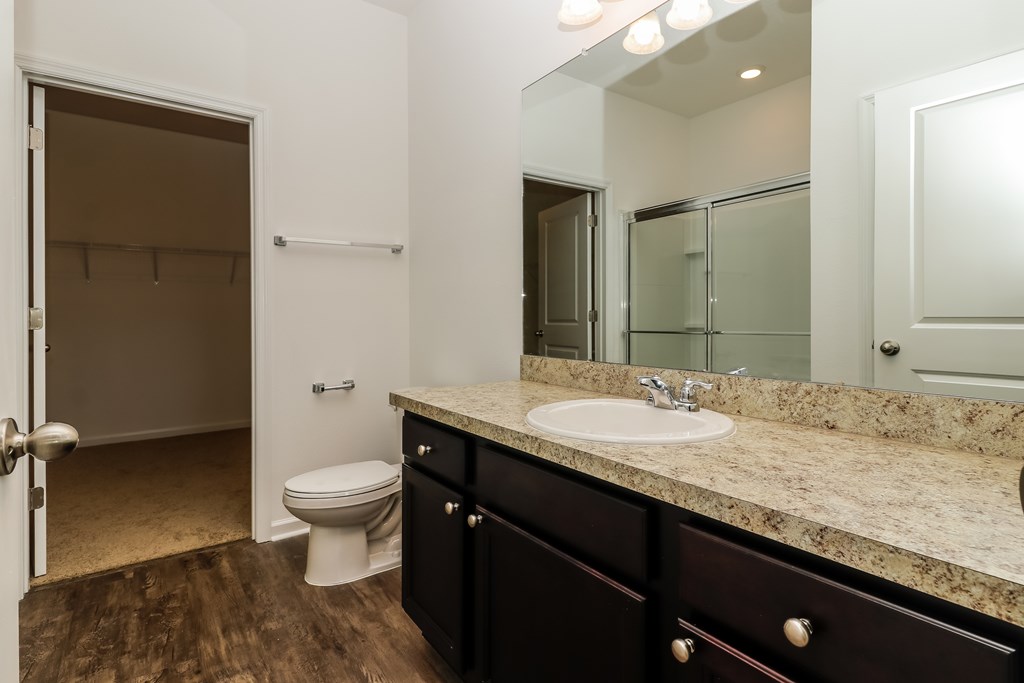 A bathroom with a toilet, sink, and mirror.
