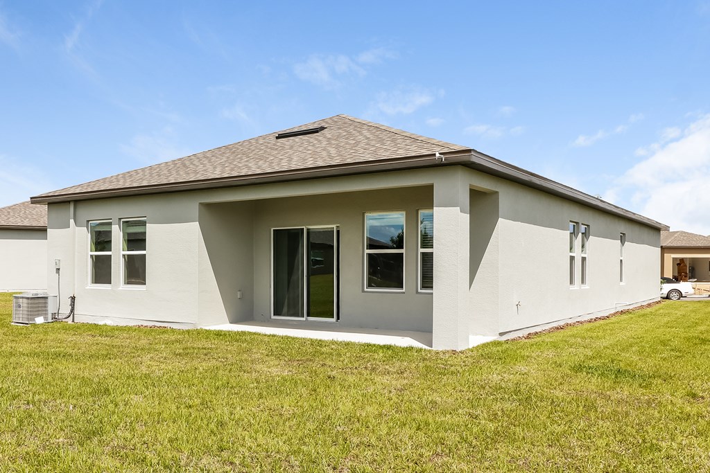 A house with a brown roof and white walls with a green lawn in front.