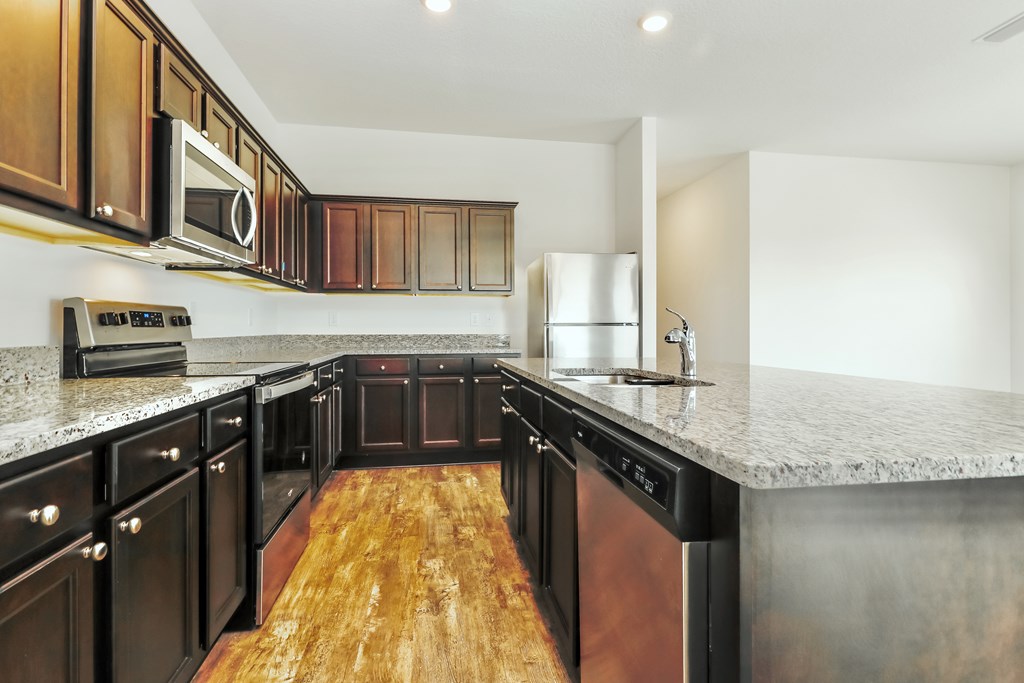 A kitchen with dark wood cabinets and a granite countertop.