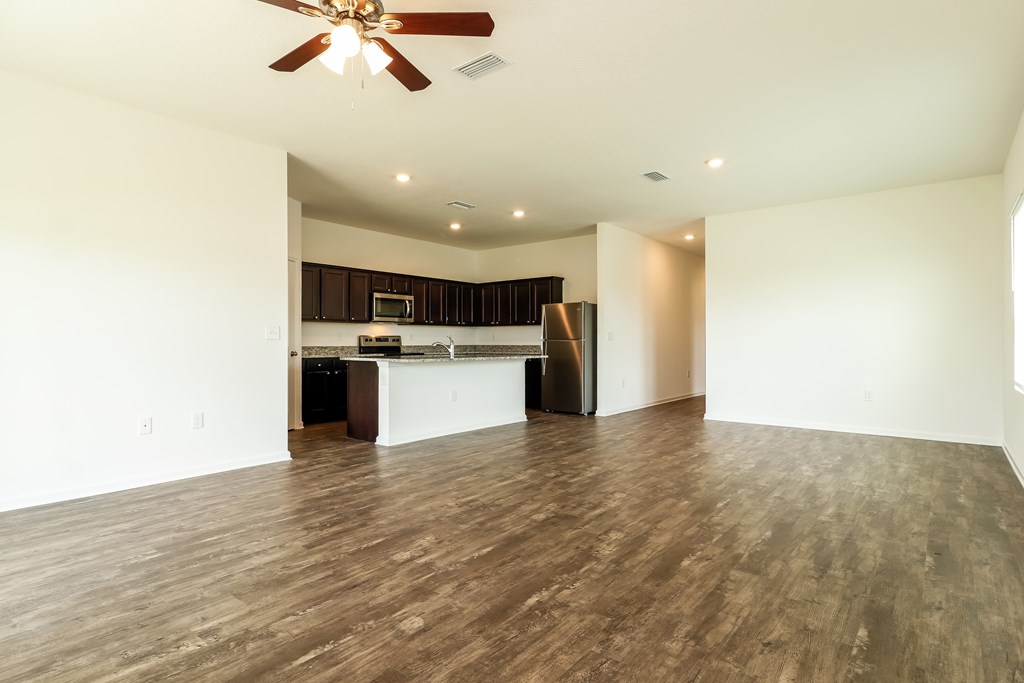 A room with a ceiling fan and wooden flooring.