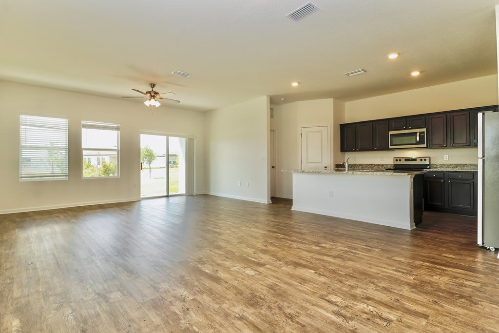 A spacious kitchen and living room with wooden floors and white walls.
