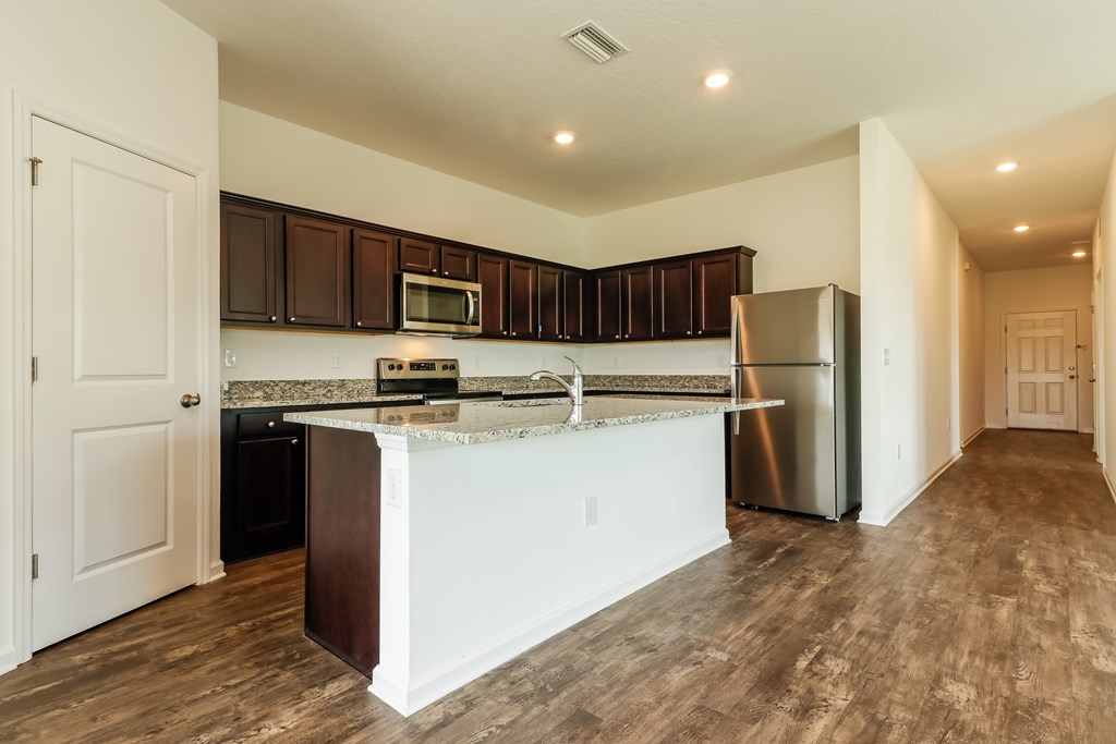 A kitchen with dark brown cabinets and a white island.