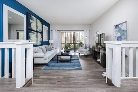 A living room with a white couch and a blue rug.