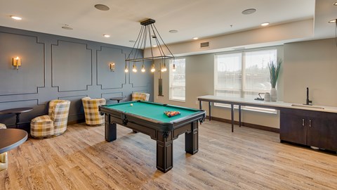 A room with a pool table and a bar area.