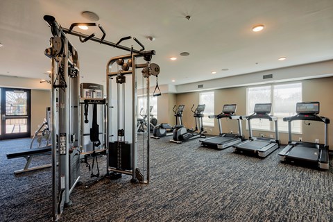 A gym with a variety of equipment including treadmills, weights, and exercise machines.
