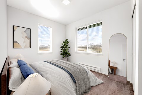A bedroom with a large bed and a small tree in the corner.