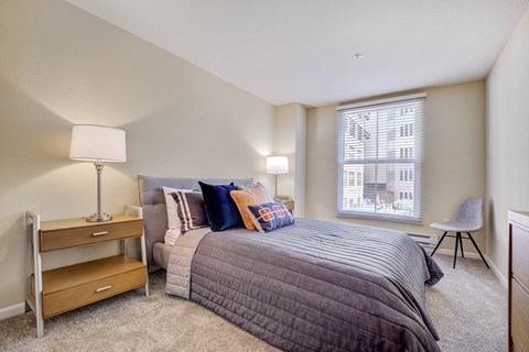 San Rafael, CA, Apartments Near Mount Tamalpais State Park - Rafael Town Center - Spacious Bedroom With Plush Carpeting, BEd, Nightstands with Lamps, Dresser, Chair, And Large Picture Window With Blinds.