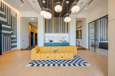 A yellow sofa sits in the middle of a room with a black and white checkered rug.