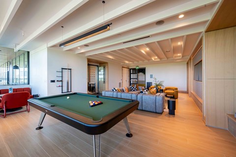 A pool table is in the middle of a room with a couch and a chair.