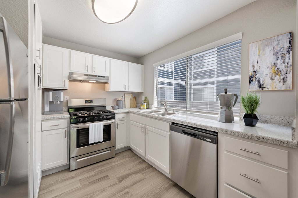 an open kitchen with stainless steel appliances and white cabinets