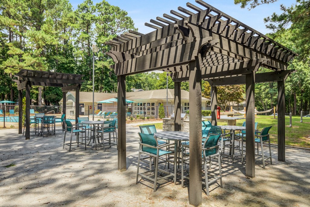a patio with tables and chairs and a wooden pergola