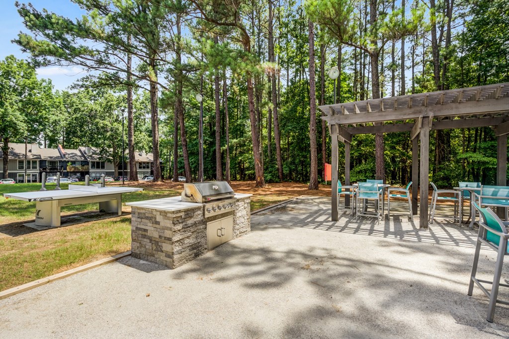 a patio with a barbecue grill and tables and chairs